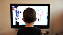 テレビを観ている子供の後ろ姿の写真
